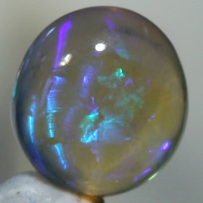 SOLID CRYSTAL OPAL High dome with blue and purple hues throughout the transparent body